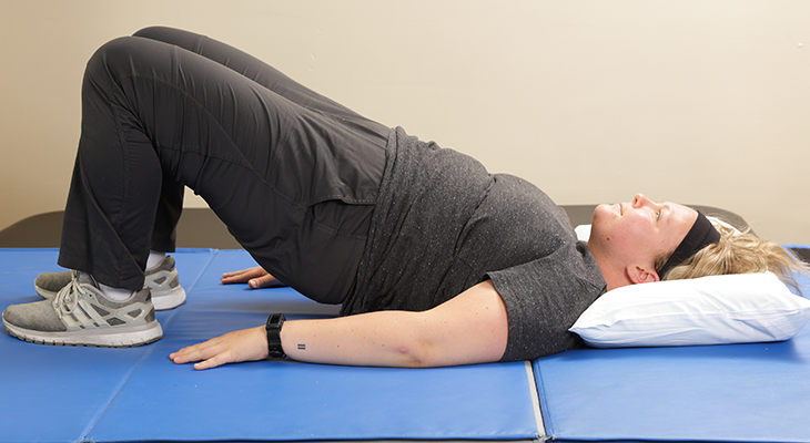 A patient demonstrates the second part of the bridges back pain excercise