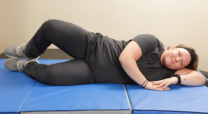 A patient demonstrates the second part of the clamshells back pain exercise.