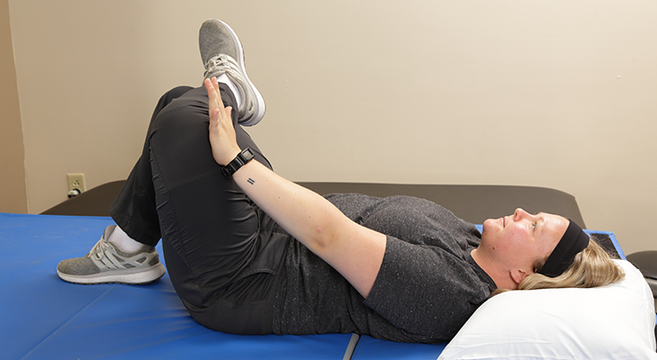 A patient demonstrates the piriformis stretch back pain exercise